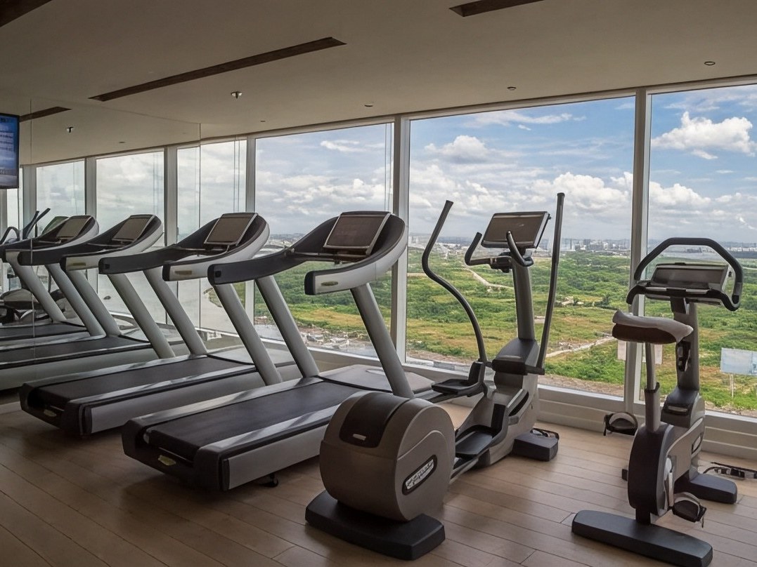 Hotel gym with treadmills and weights in front of a wall of windows