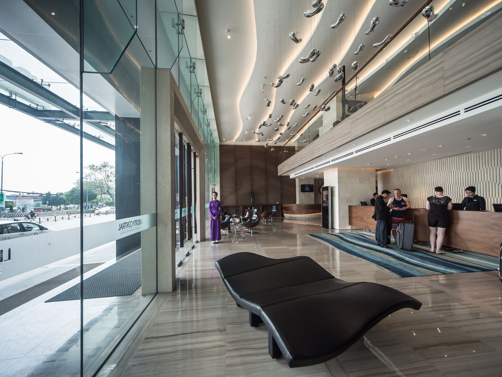 Bright hotel lobby with a long reception desk and glass doors to the street