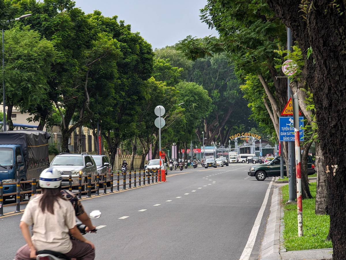 Saigon avenue at dusk with cars, motorbikes and tall trees