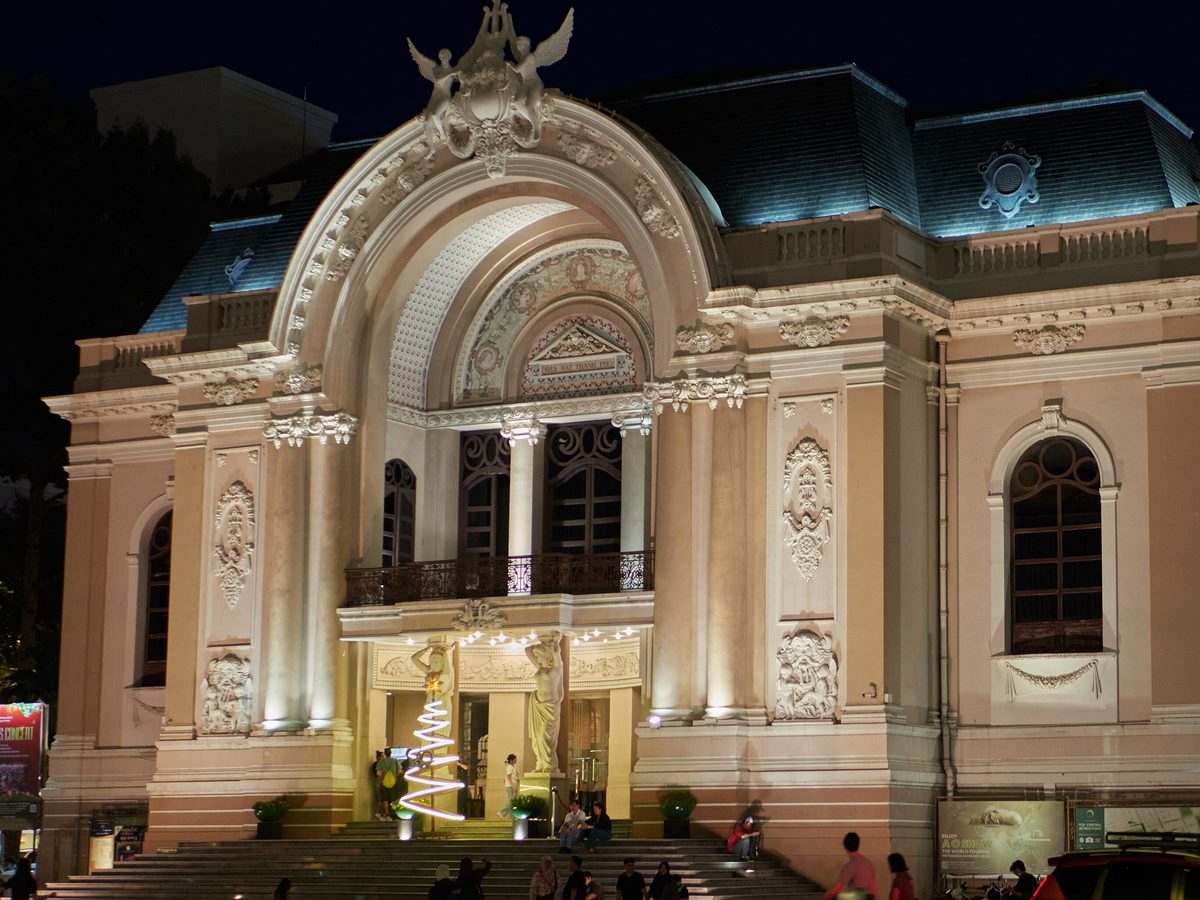 Saigon Opera House lit up at night with light trails of passing traffic