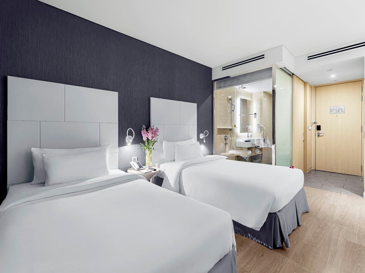 Twin room with two white beds, a desk and a floor-to-ceiling window