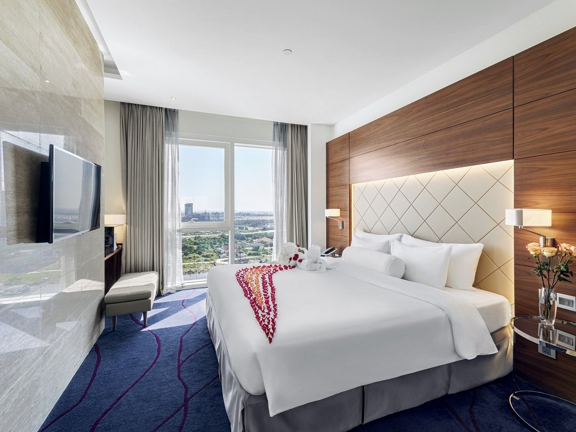 Suite bedroom with a king bed, wood-panelled wall and wide windows