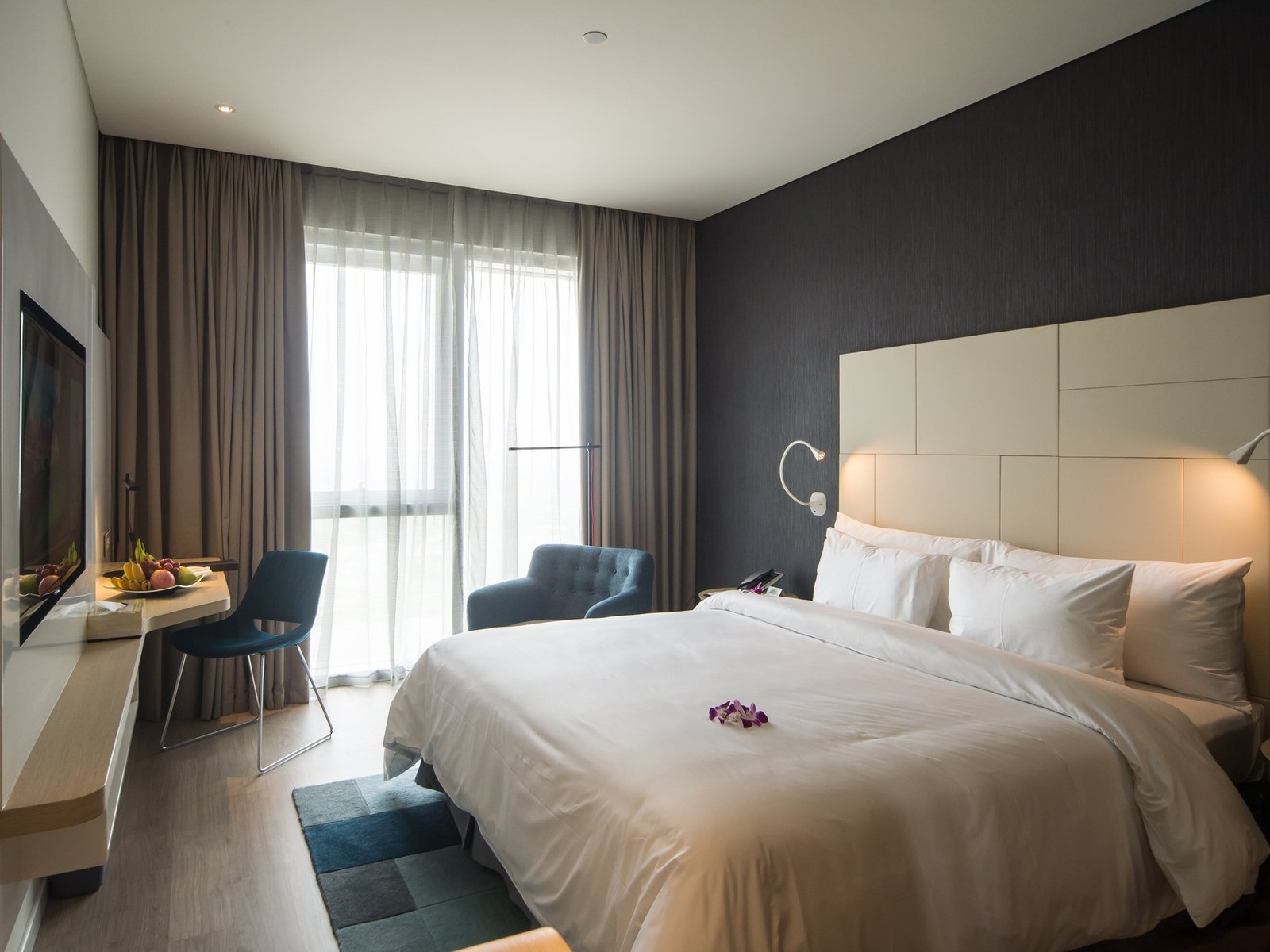 Executive room with a king bed, an armchair and a tall window onto the city