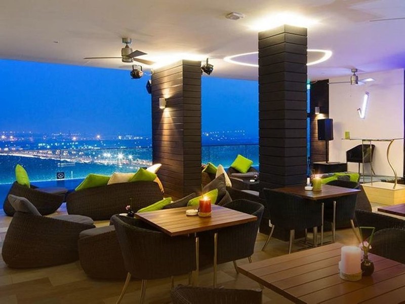 Rooftop bar with lounge chairs, candles and the river lit up at dusk