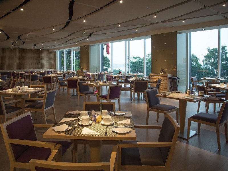 Hotel restaurant dining room with tables set beside tall windows